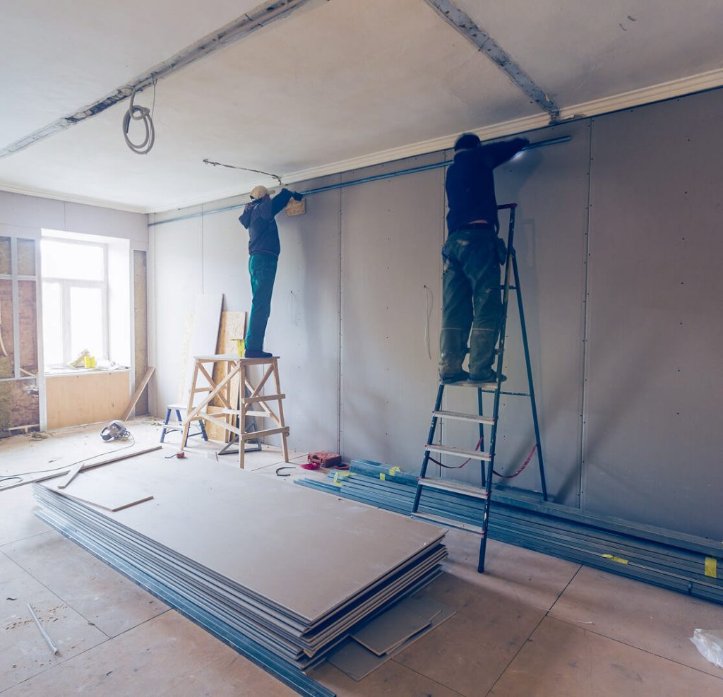men on ladders installing drywall