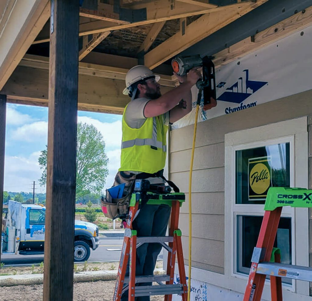 man drilling nails into house