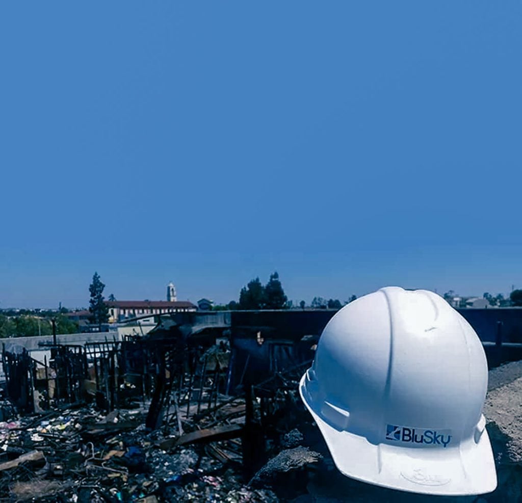 BluSky work hat on ground in front of property destruction