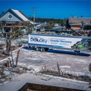 BluSky Storm Recovery truck in front of destroyed property