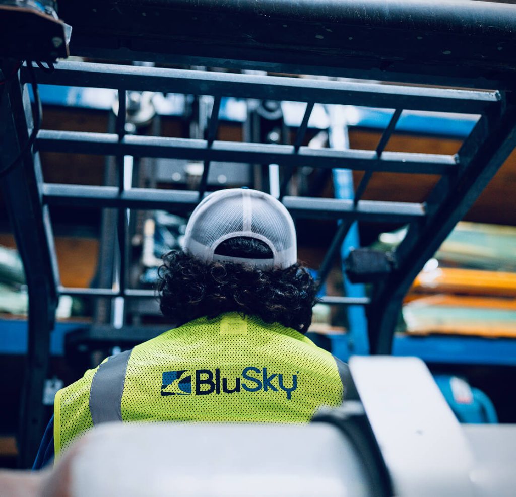 man in BluSky vest operating heavy machine