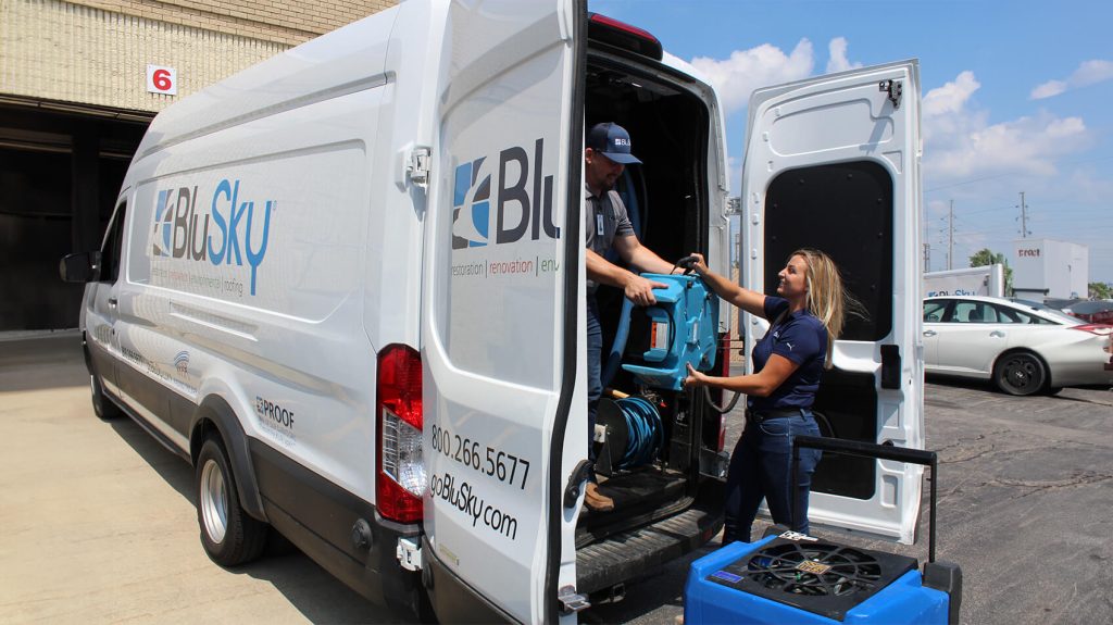 woman helping carry equipment out of the blusky van
