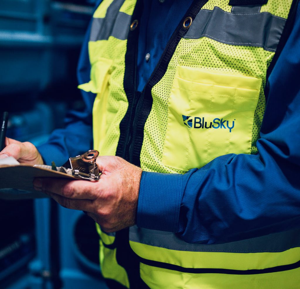 man in BluSky vest writing on clipboard