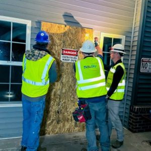 restoration workers boarding up damaged home property