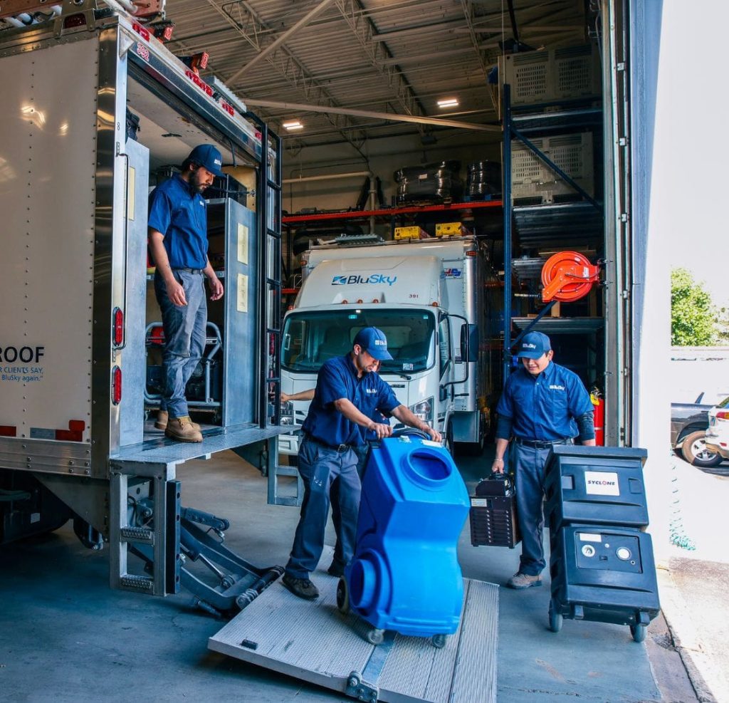 restoration workers loading equipment into a truck