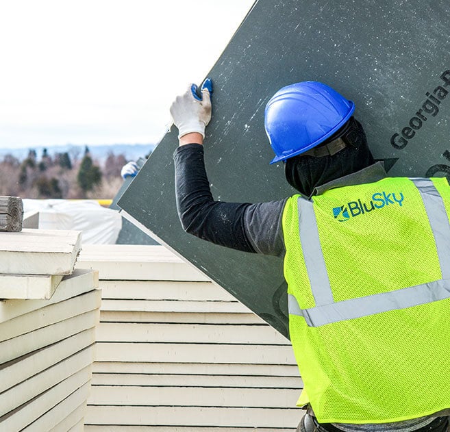 blusky employee carrying roof materials