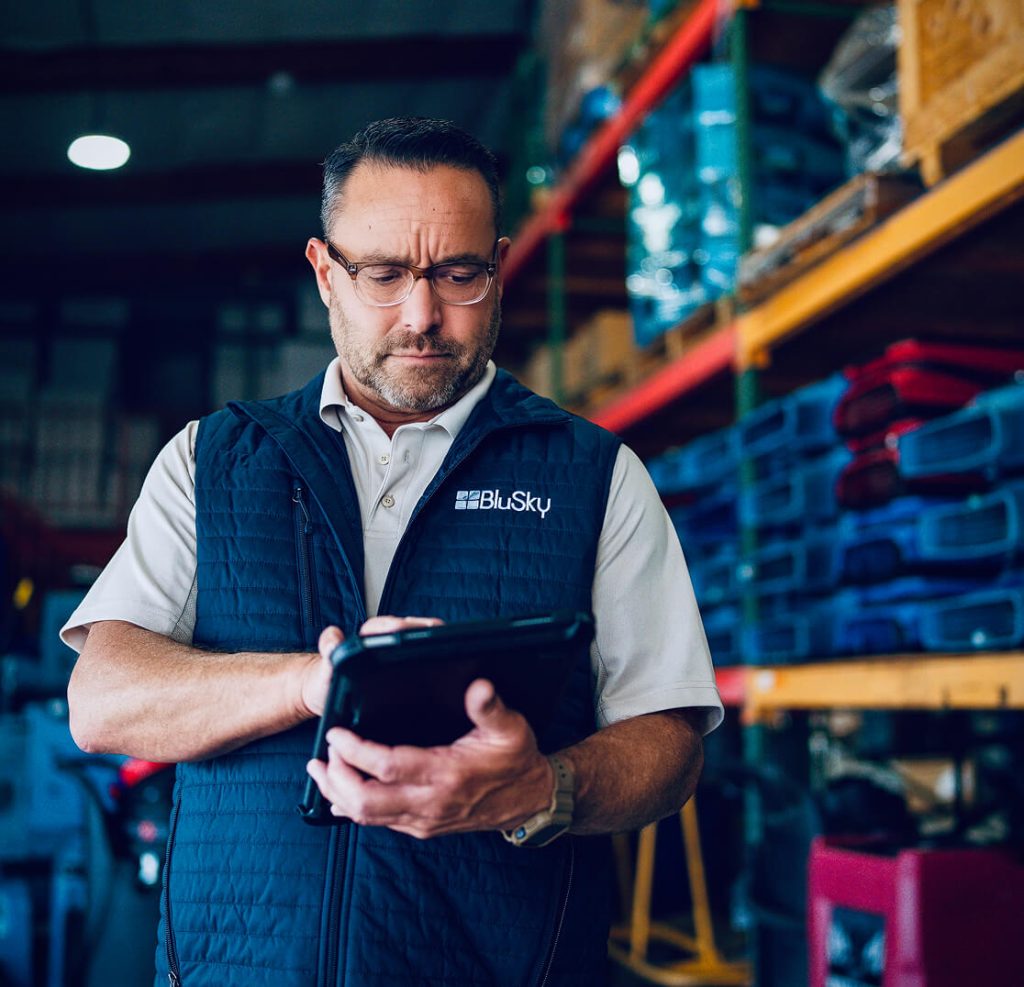 man in BluSky vest typing on tablet